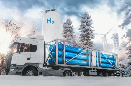Lorries with hydrogen trailers in winter in front of H₂ storage tanks and wind turbines – symbolic image for the transport and storage of green hydrogen.