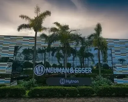 Exterior view of the NEUMAN & ESSER facility with HYTRON signage, surrounded by palm trees.