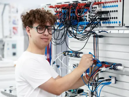 Student adjusts wiring on an electrical training setup during a hands-on exercise.