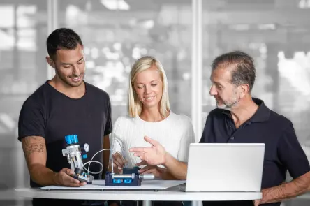 Group of learners examining a pneumatic component with a laptop.
