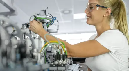Side view of a woman  working on an automation system with cables and control components.