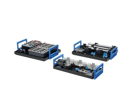 Two learners review sensor data on a handheld device at an automation training setup.